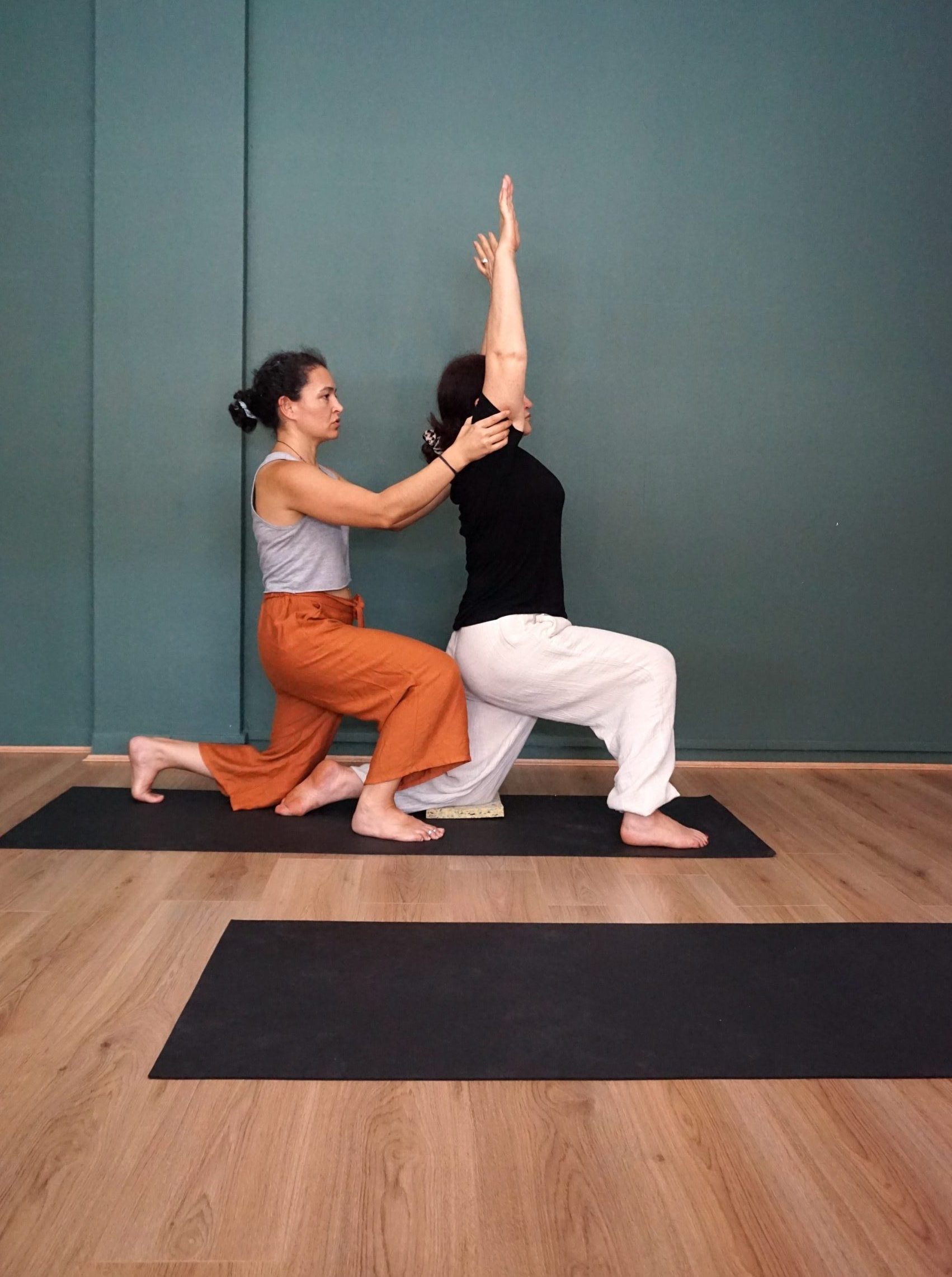 Low Lunge Yoga Pose practising and assisted by a teacher